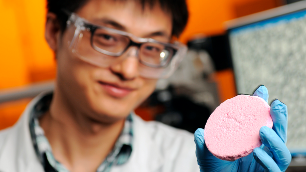 Yi Zhang, a graduate student holding a porous solid material prepared from a capillary foam. (Credit: Gary Meek)