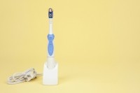 An electric toothbrush on yellow background