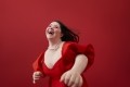 Happy young woman with with down syndrome laughing against red background. © Getty Images - Klaus Vedfelt